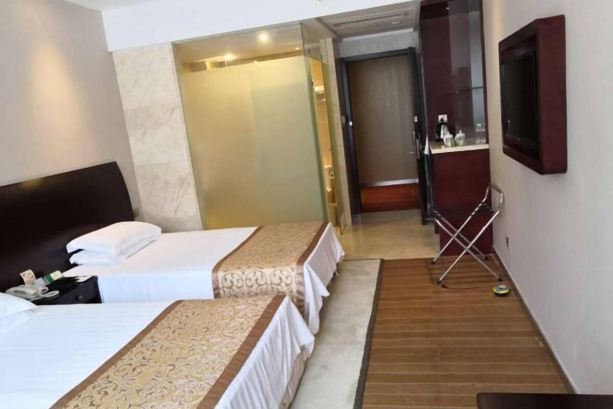 A hotel room with two beds, a TV, a mirror, and a small table.