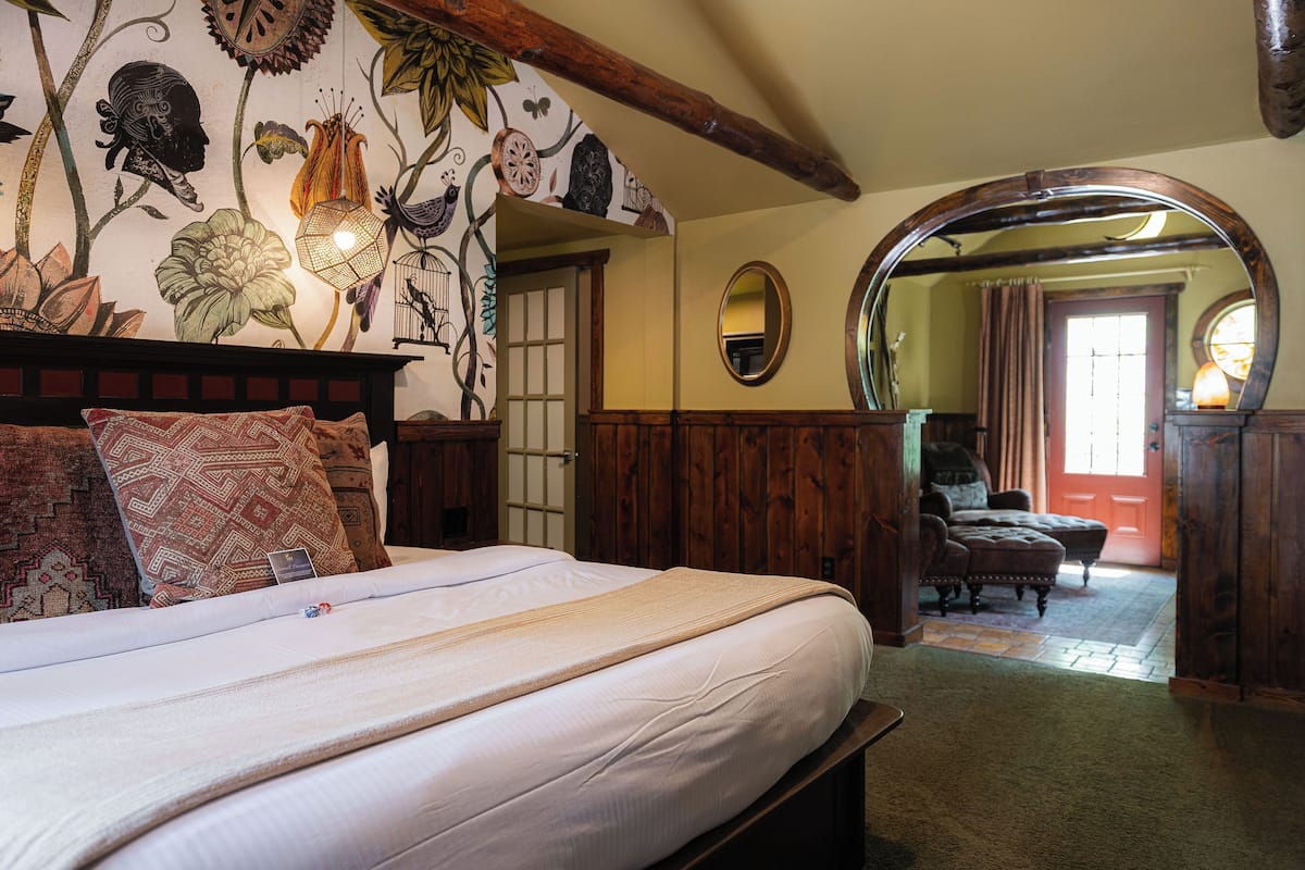 A traditional room with a large bed, wooden headboard, and a floral-patterned wall.