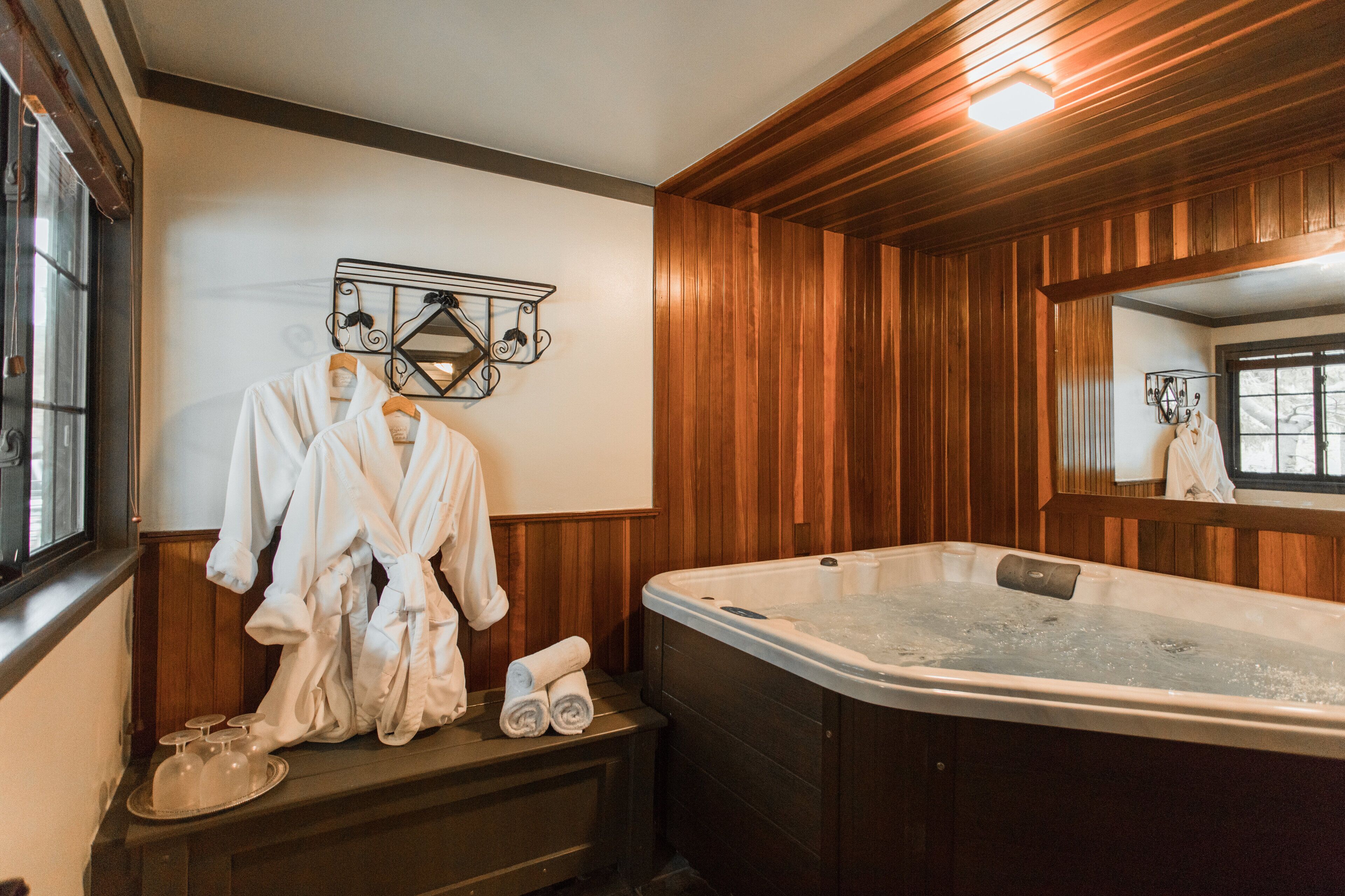 A bathroom with a wooden vanity, a large bathtub, and a mirror.