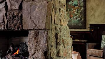 A stone fireplace with a fire, a painting on the wall, and a wooden floor.