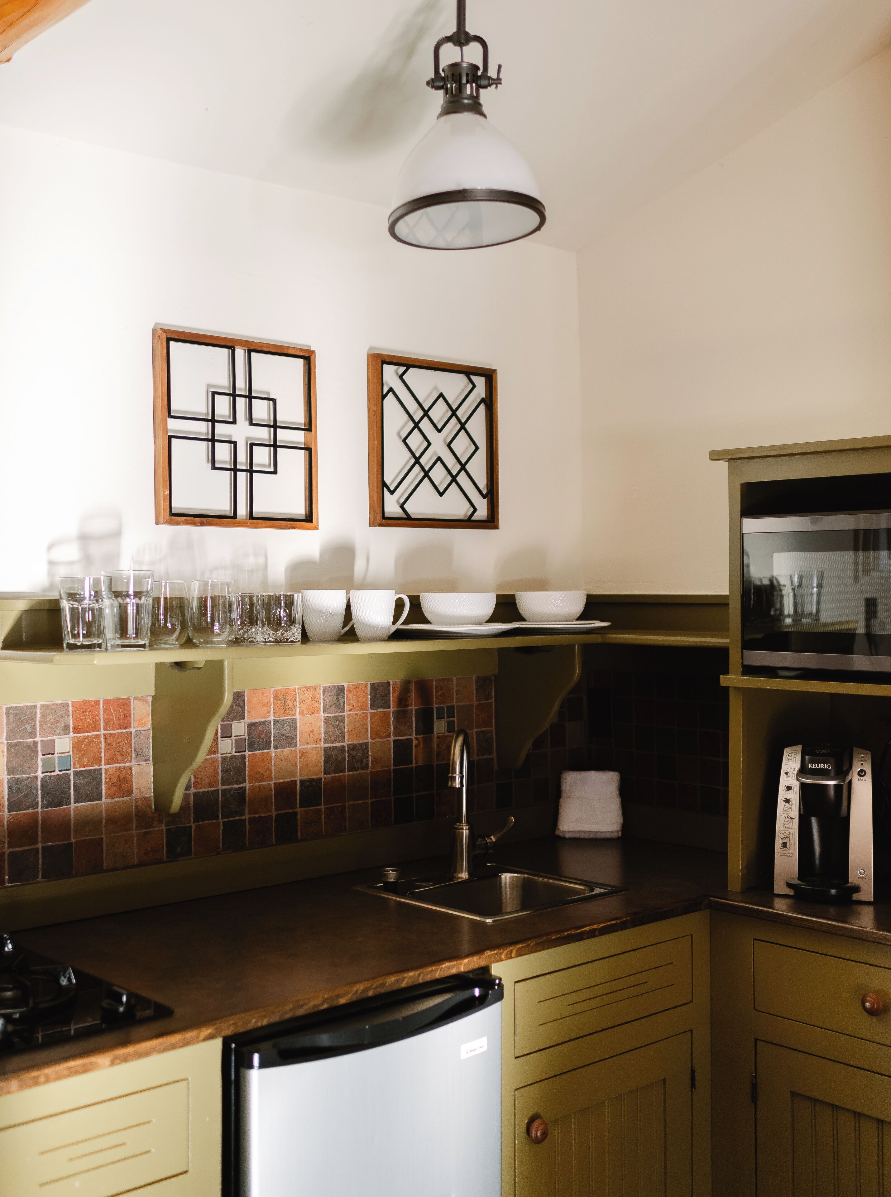 Una cocina con salpicadero de azulejos, cafetera y lavabo.