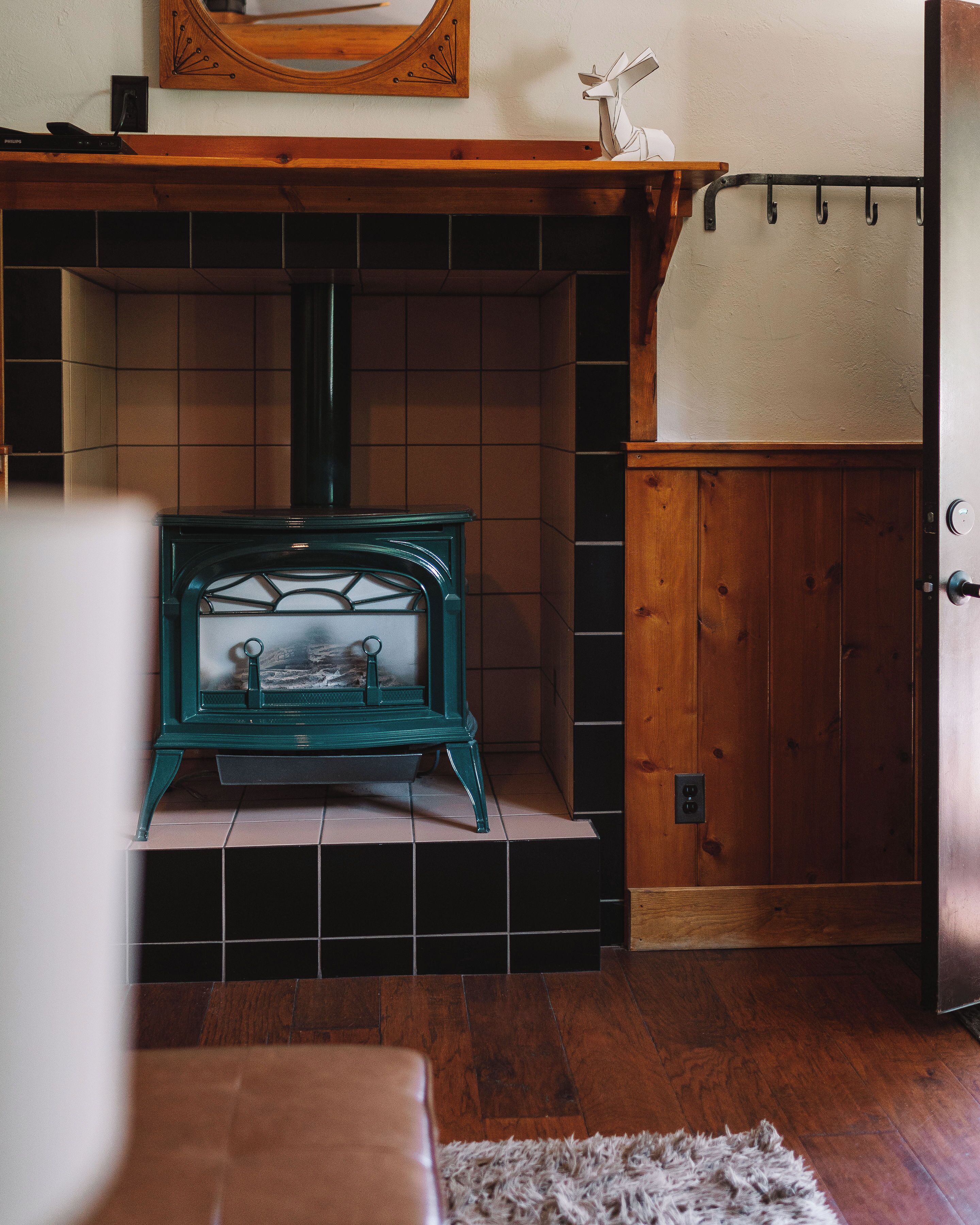 A room with a wood-burning stove, a wooden door, and a tiled fireplace surround.