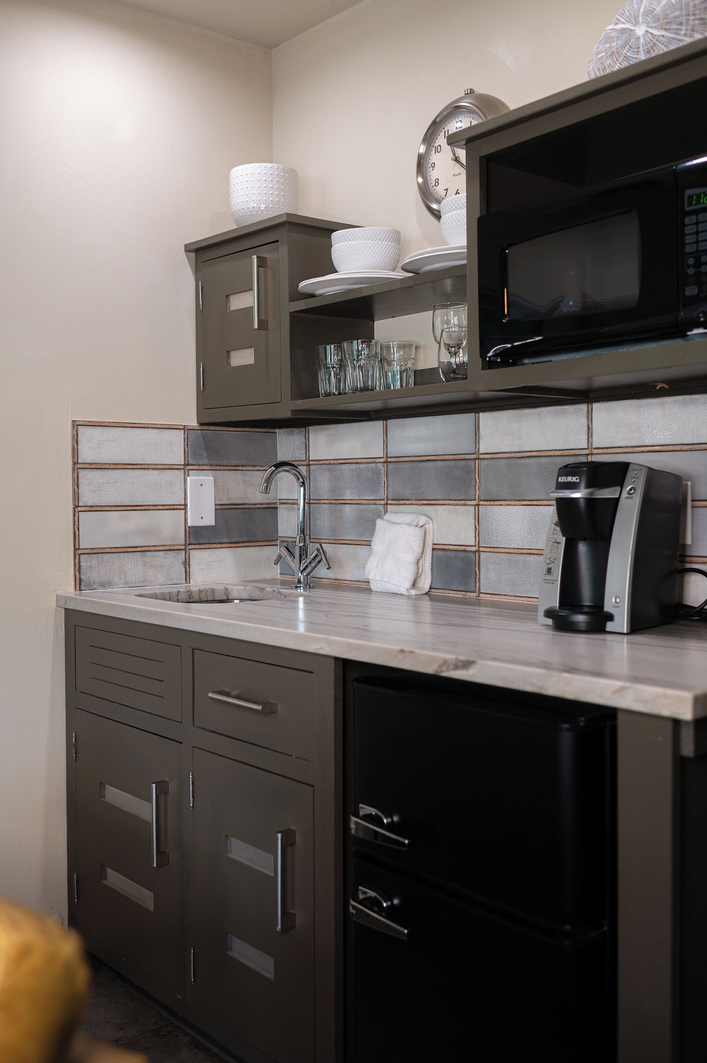 Une cuisine moderne équipée d’un four à micro-ondes, d’une machine à café et d’un évier.