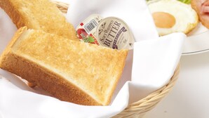 A basket containing a slice of toasted bread, a container of soft whipped butter, a plate with a fried egg, and a side salad. - Fine Misaki Minami Ichibanchi (Misaki)