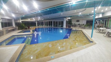Una piscina cubierta, una piscina al aire libre, tumbonas