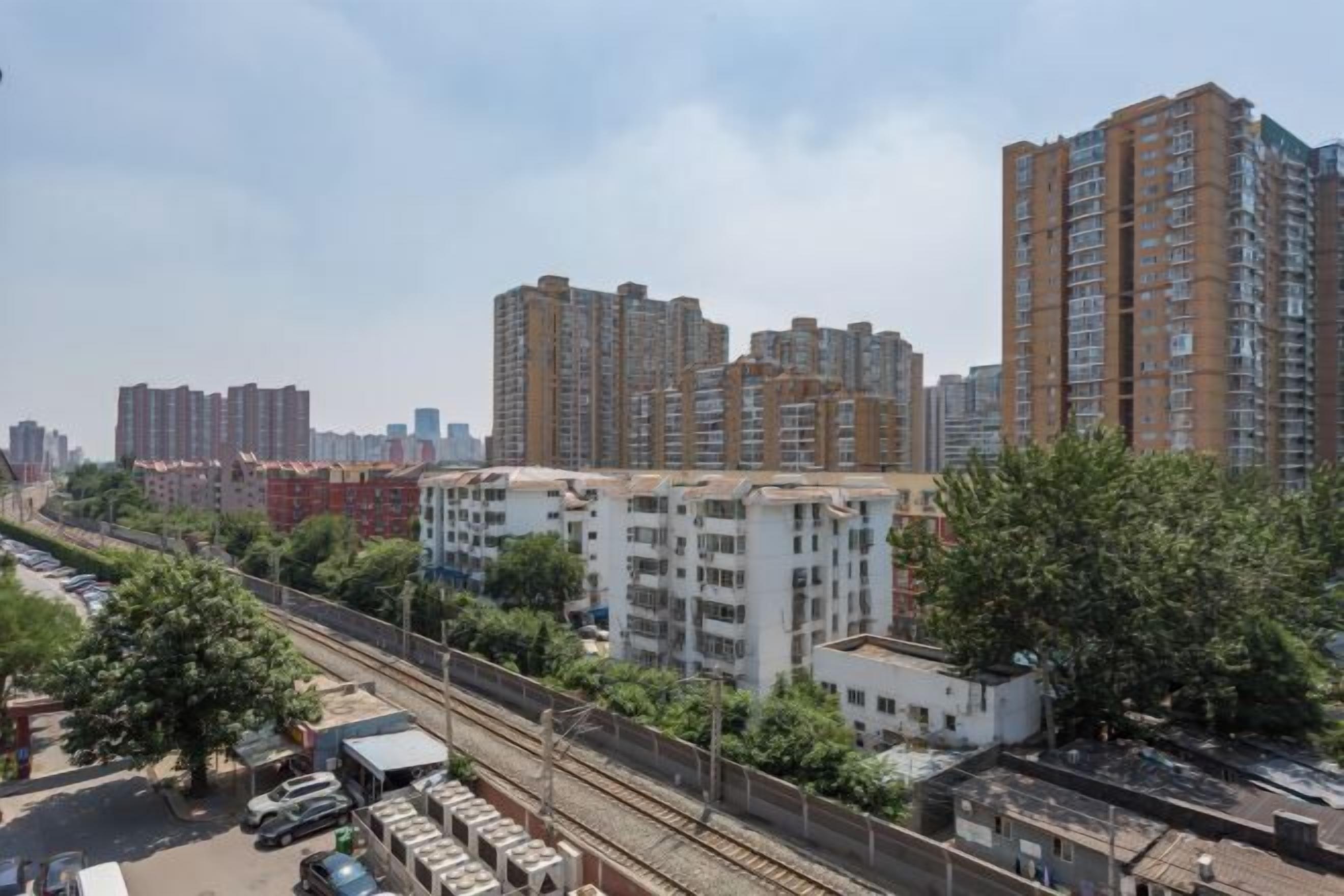 A high-rise residential building with multiple floors, surrounded by other buildings and greenery.
