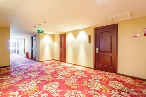 A hotel corridor with carpeted flooring, wooden doors, and a visible exit sign. - Guangyun Hotel Beijing (Beijing)