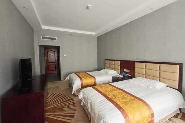 Habitación de hotel con dos camas, televisión, escritorio y puerta.