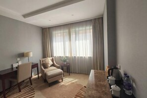 A hotel room with a desk, chair, sofa, and a large window with curtains. - Guangyun Hotel Beijing (Beijing)