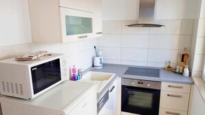 Kompakti keittiö, jossa on mikroaaltouuni, uuni ja vedenkeitin.