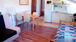 Un espacio habitable compacto con comedor, kitchenette y cama.