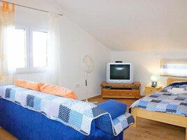 A bedroom with two beds, a TV, a fan, and a nightstand with a lamp.