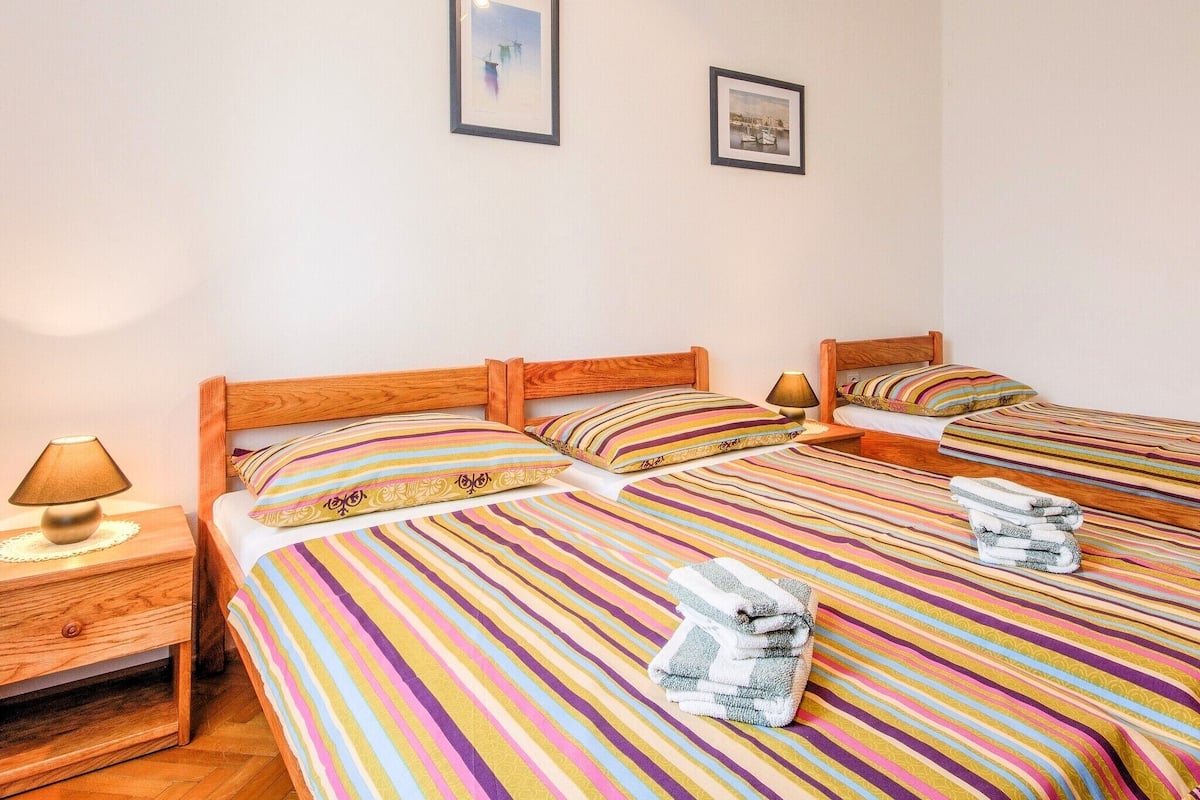 A hotel room with two beds, striped bedding, wooden headboards, and two framed pictures on the wall.