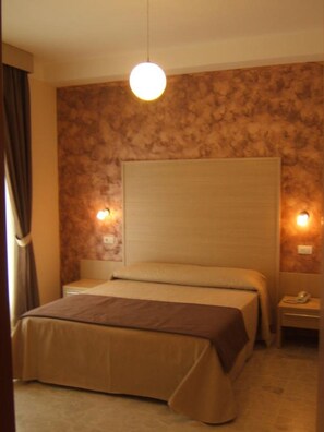 A hotel room with a bed, a nightstand, a lamp, and a wall with a textured pattern. - Hotel Ede (Caramanico Terme)