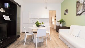 Een moderne keuken met witte kasten, een eettafel met stoelen, een witte bank en een potplant.