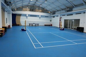 An indoor sports hall with a blue floor, tables, and benches along the walls. - CY Journalists' Home Hotel（Dongzhimen Hospital Dongsishitiao Subway Station Branch） (Beijing)