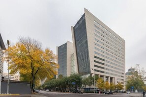 Un immeuble à plusieurs étages doté d’une architecture moderne, caractérisé par un angle bien marqué et un toit plat.