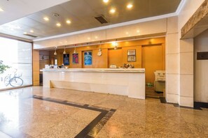 A hotel reception area with a marble floor, a reception desk, and a glass door leading outside. - CY Journalists' Home Hotel（Dongzhimen Hospital Dongsishitiao Subway Station Branch） (Beijing)