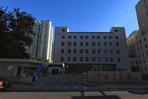 A multi-story building with a flat facade, a gated entrance, and a clear sky above. - CY Journalists' Home Hotel（Dongzhimen Hospital Dongsishitiao Subway Station Branch） (Beijing)