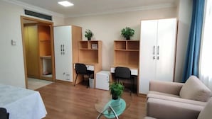 Een moderne woonkamer met een glazen salontafel, een bank, een bureau en een kledingkast.
