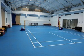 Une salle de sport intérieure dotée d’un sol bleu, de tables, de bancs et d’un mur d’escalade.