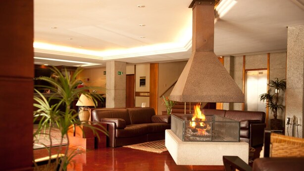 A lobby with a fireplace, leather sofas, and a wooden floor.