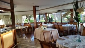 A restaurant with round tables, chairs, and a view of the outdoors.