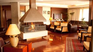 A modern living room with a fireplace, leather sofas, and a television.
