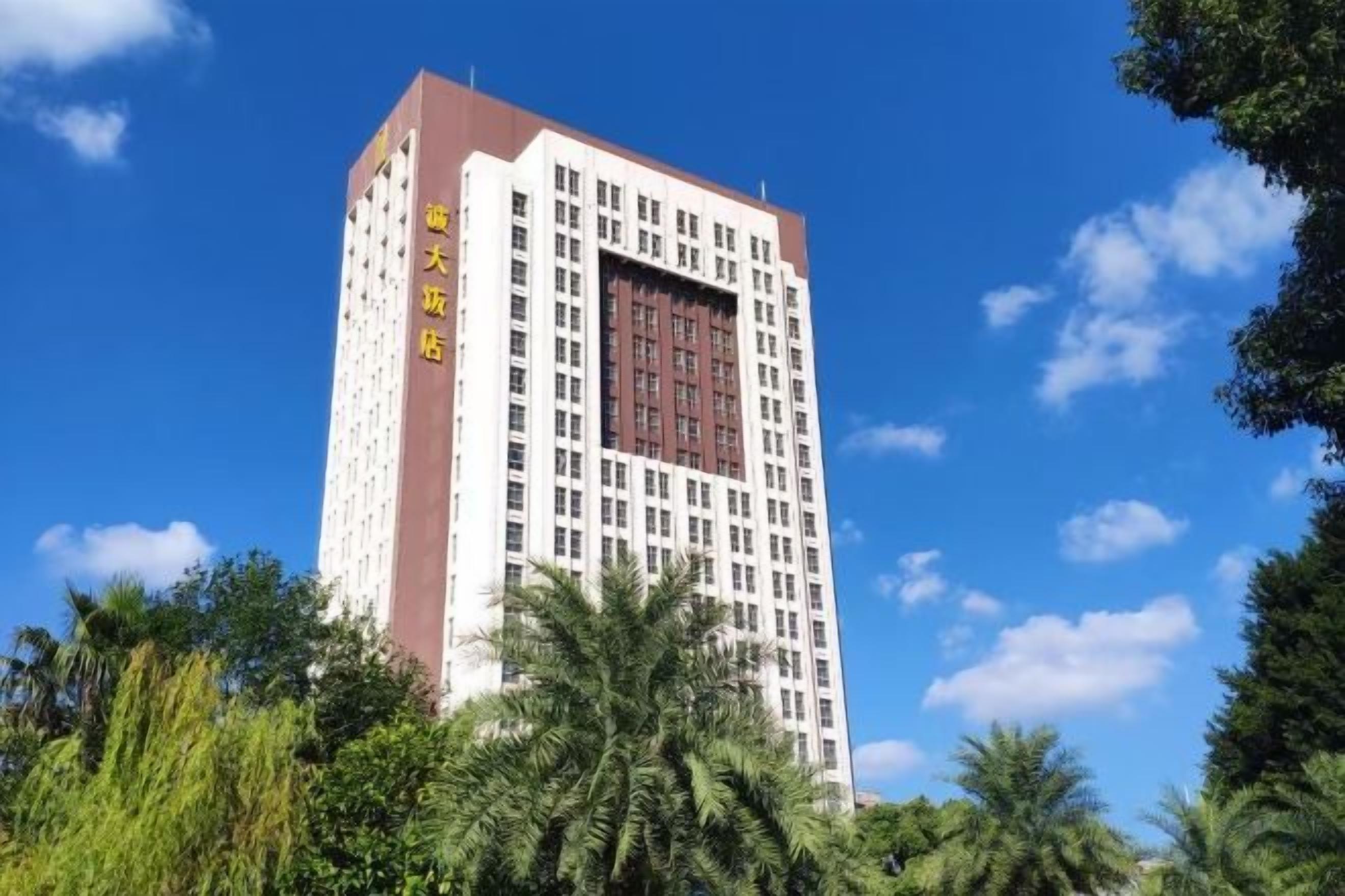 A multi-story hotel with a prominent entrance, surrounded by lush greenery.