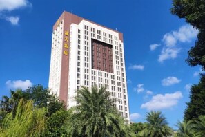 A multi-story hotel with a prominent entrance, surrounded by lush greenery. - Chengda Hotel (Longgang)