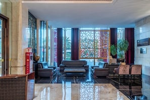 A lobby with a reception desk, seating area, and large windows. - Chengda Hotel (Longgang)