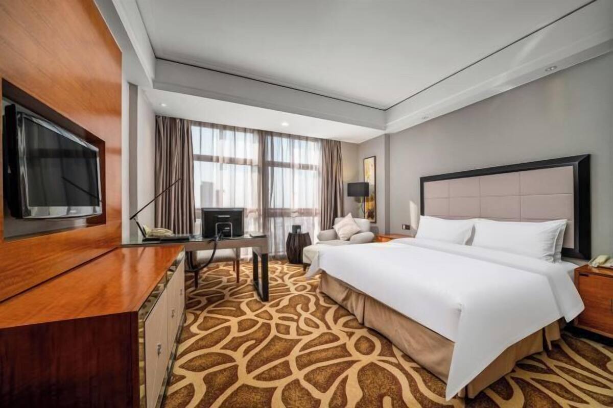 Une chambre d’hôtel avec un grand lit, un bureau, une télévision et une vue sur l’extérieur.
