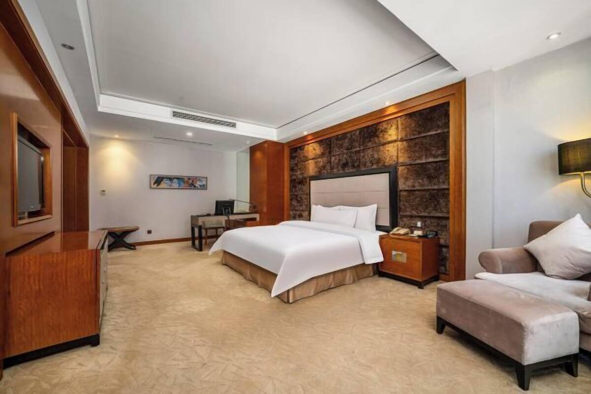Une chambre d’hôtel avec un grand lit, un bureau, une chaise et un téléviseur.
