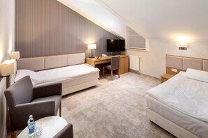 A hotel room with two beds, a desk, a chair, a TV, and a small table with a bottle and glasses. - Eva Park Life Spa (Konstancin-Jeziorna)