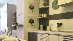 Eine moderne Küche mit Essbereich, in Weiß- und Grautönen gehalten, mit Uhr und Kaffeemaschine.