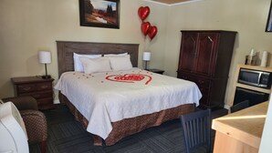 A hotel room with a bed, a wooden cabinet, a microwave, a desk, and a chair. - Fiesta City Motel (Montevideo)