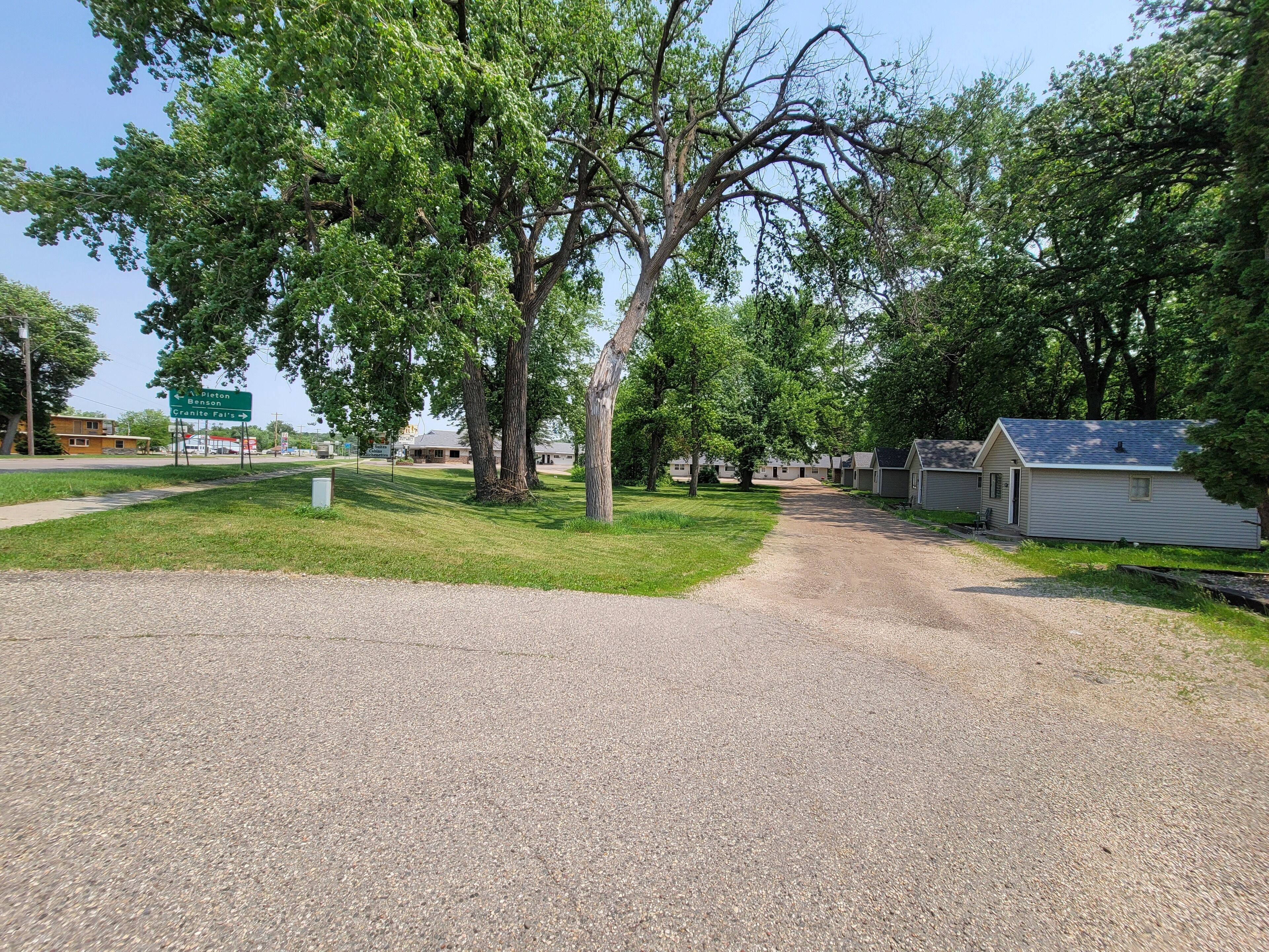 A gravel path leading to a row of cabins with a sign indicating directions to nearby locations.