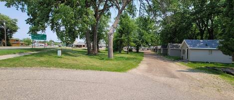 A gravel path leading to a row of cabins with a sign indicating directions to nearby locations.