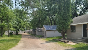 A row of single-story mobile homes with a gravel driveway, surrounded by trees. - Fiesta City Motel (Montevideo)