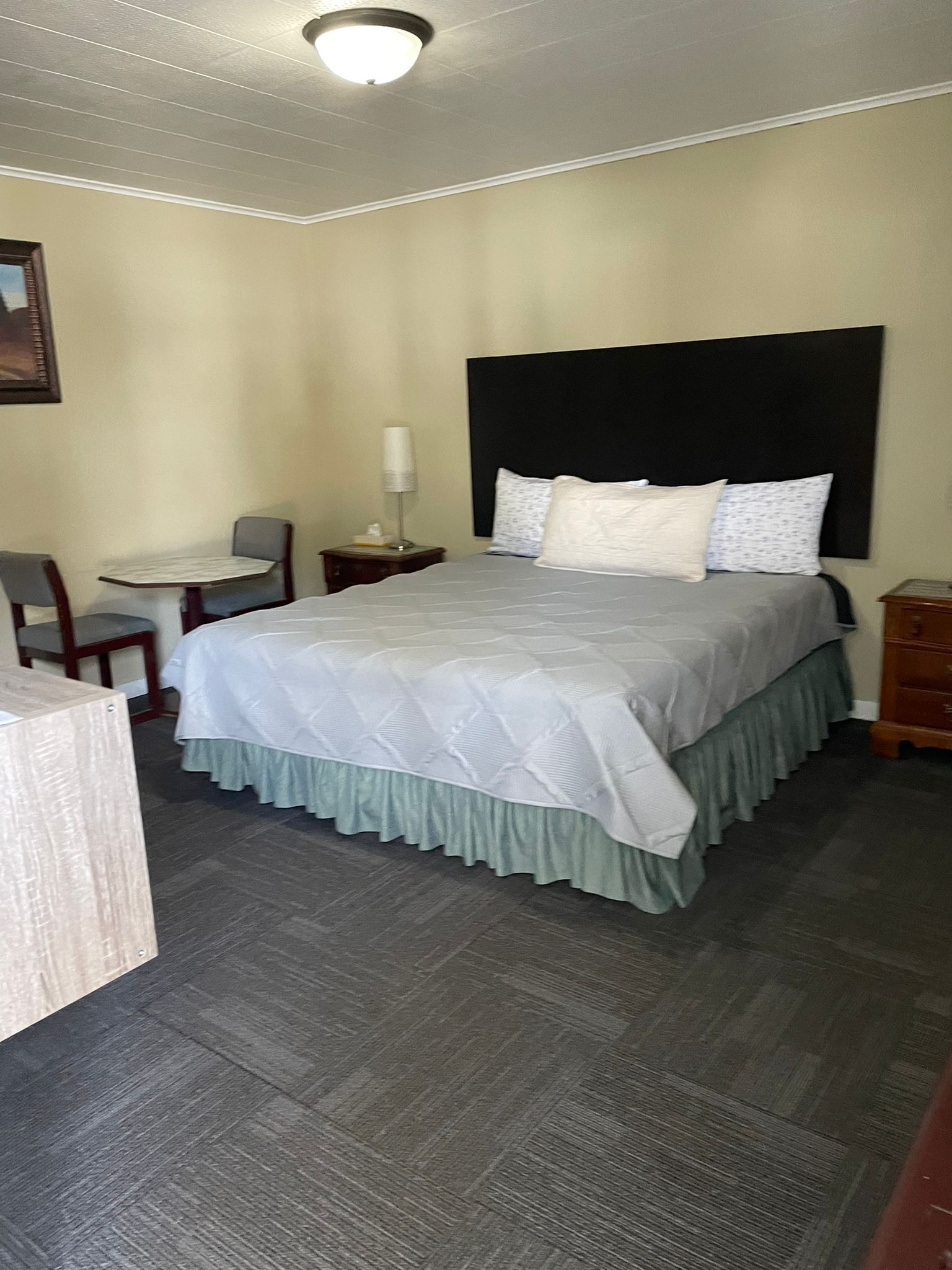 A neatly arranged hotel room with a bed, a small desk, and a chair.