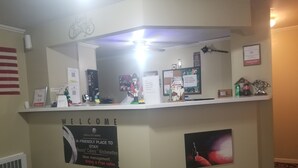 A hotel reception desk with a 'Welcome' sign, a 'Fiesta City Motel' sign, and a 'Fair 4.8' rating. - Fiesta City Motel (Montevideo)