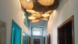 A hallway with a wooden floor, teal doors, and a ceiling with woven light fixtures. - Le Hublot (Abomey-Calavi)