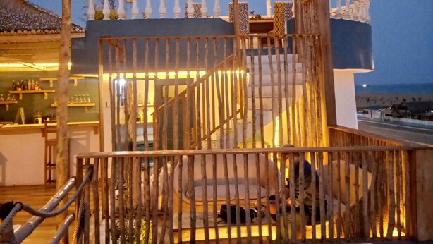 A wooden deck with a railing, a covered seating area, and a view of the sea. - Le Hublot (Abomey-Calavi)