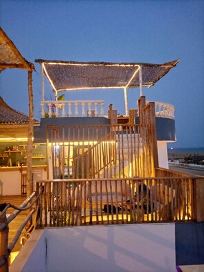 A wooden deck with a railing, a covered seating area, and a view of the sea. - Le Hublot (Abomey-Calavi)
