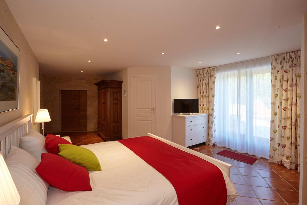 Ein Hotelzimmer mit einem Bett, einem Fernseher, einem Kleiderschrank und einer Tür zu einem anderen Raum.