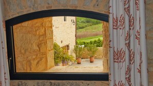 A stone archway leading to a courtyard with potted plants and a view of a green landscape. - Chambres d'hôtes La Tour de Ginaillac (Les Arques)