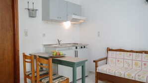 Une cuisine compacte équipée d’une cuisinière, d’un évier et d’une petite table à manger avec des chaises.