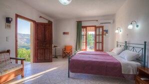Une chambre à coucher avec un lit, une chaise, une table et une vue sur l’extérieur.
