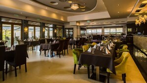 Un restaurante con un interior moderno, que cuenta con una amplia zona de comedor con mesas y sillas, una barra y grandes ventanales que permiten la entrada de luz natural.