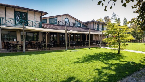 A building with outdoor seating and a lawn. - Duna Garden Hotel (Budapest)